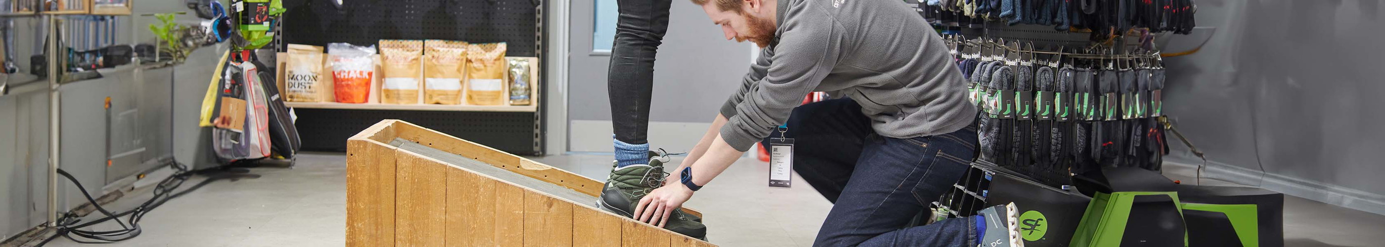 An image of an in-store expert, fitting a customer for walking boots 